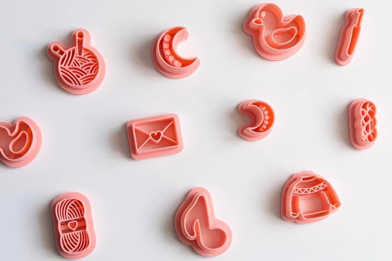 Set of pink cookie cutters on a white surface with dried plants.